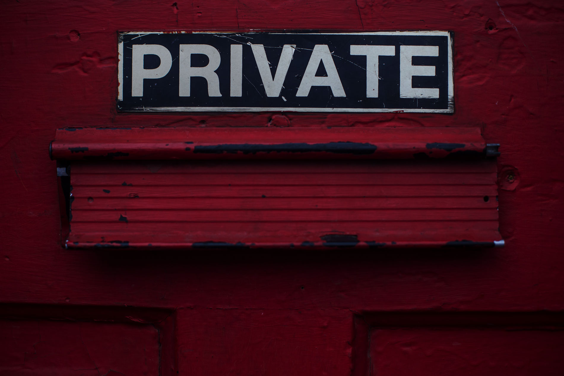 Blue and white Private sign over post slot on red door